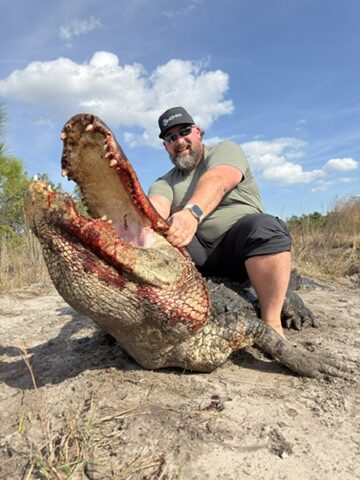 A hunter with an open-mouth trophy alligator at Brawler Creek Ranch