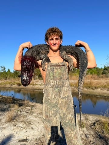 A young hunter holding his harvested alligator at Brawler Creek Ranch